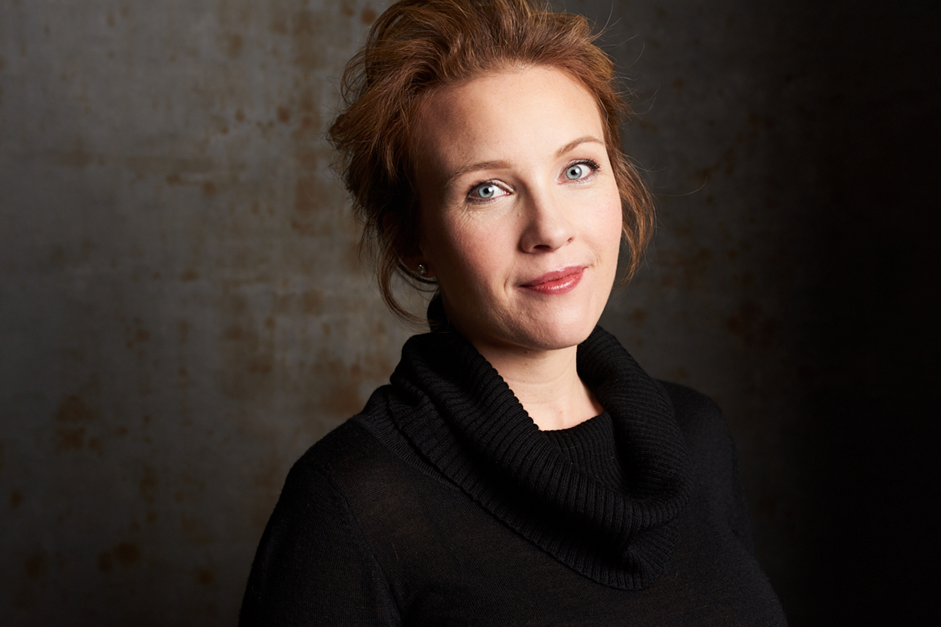 Headshot of mezzo-soprano Sasha Cooke looking directly at the camera against a dark background.